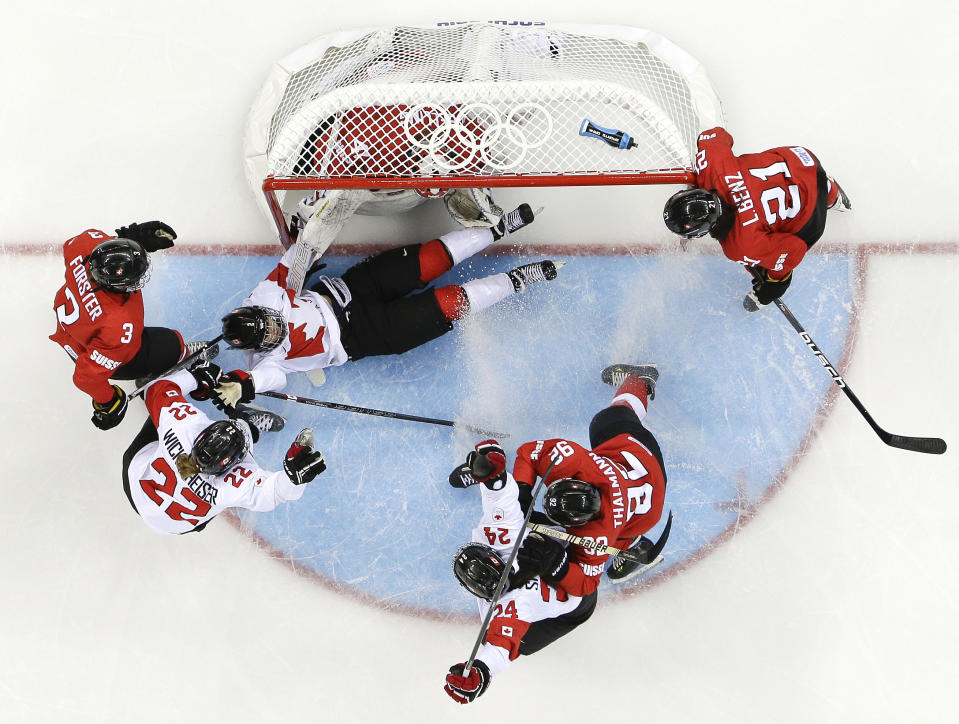 Meghan Agosta-Marciano of Canada, center, reacts as she slides into the net while attempting to score against Goalkeeper Florence Schelling of Switzerland during the third period of the 2014 Winter Olympics women's semifinal ice hockey game at Shayba Arena, Monday, Feb. 17, 2014, in Sochi, Russia. (AP Photo/Matt Slocum)