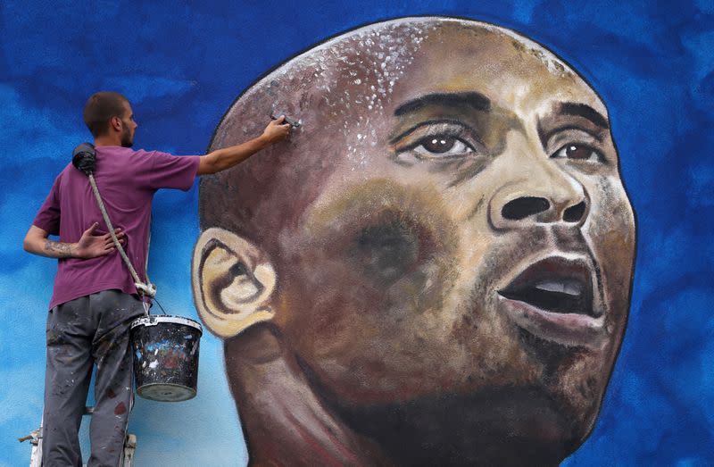 Artist Deni Bozic (27) paints the last details on his tribute mural honoring former Los Angeles Lakers basketball star Kobe Bryant on a school building wall in Gradiska