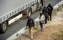 Migrants walk alongside vehicles on the route leading to the Eurotunnel in Coquelles near Calais, northern France on July 29, 2015