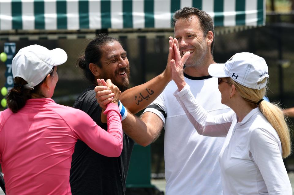 Tennis enthusiasts Sue Bushman, left, and Sherri Grace, right, join former ATP pros Guillermo Canas, second left, and Robert Lindstedt following a few volleys to raise money for First Serve USA.