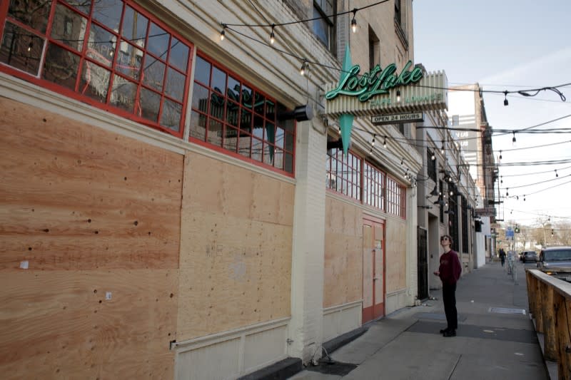 A delivery driver waits for a takeout order near the boarded up windows and doors of Lost Lake Cafe and Lounge, as authorities prohibit all dining inside restaurants during the coronavirus disease (COVID-19) outbreak, in Seattle