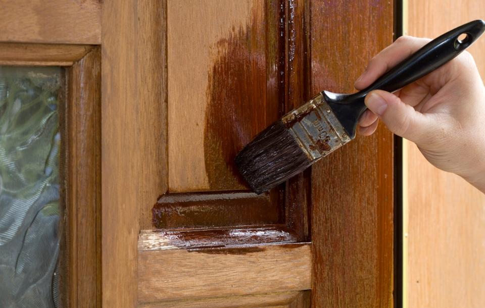 paint brush sealing wood on wooden door