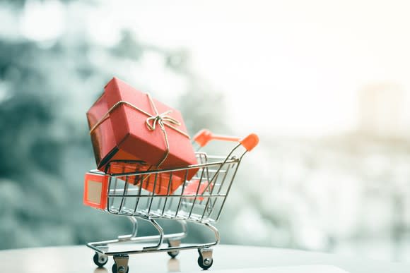 A miniature shopping cart with a wrapped gift inside.