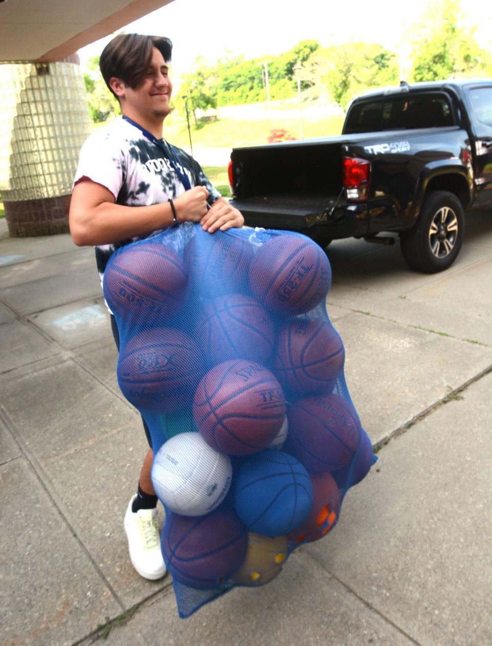 Ryan Perry, 18, of South Windham, carries a bag of basketballs into Shepard Hill Elementary School for himself and other staff counselors for the Plainfield Summer Recreation Program.