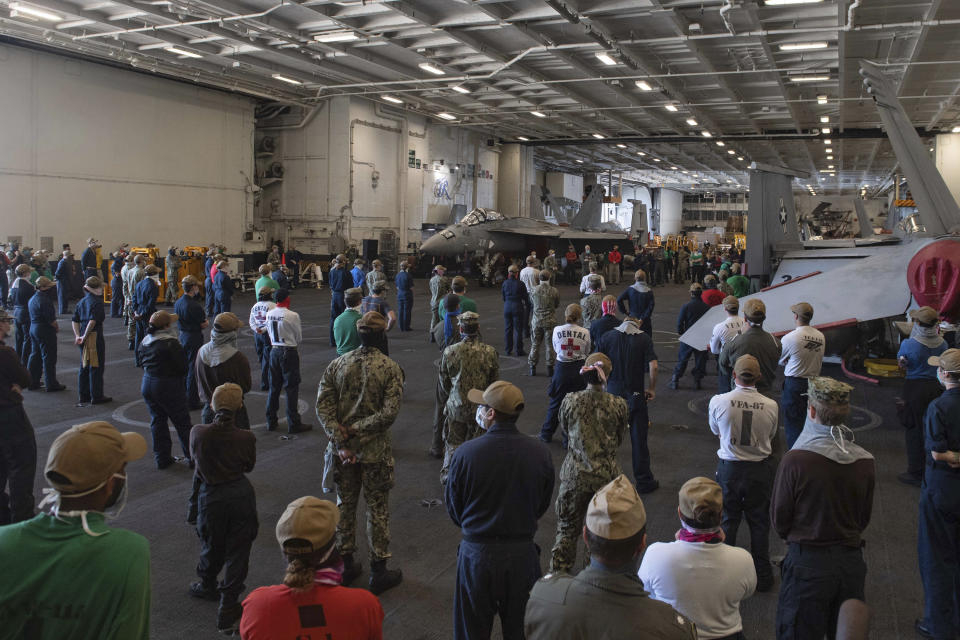 In this photo taken April 7 2020, provided by the U.S. Navy, sailors and staff assigned to the aircraft carrier USS Theodore Roosevelt listen as Vice Adm. William Merz, commander of the U.S. 7th Fleet, answers questions during a visit to the ship at Naval Base Guam. People in Guam are used to a constant U.S. military presence on the strategic Pacific island, but some are nervous as hundreds of sailors from the coronavirus-stricken Navy aircraft carrier flood into hotels for quarantine. Officials insist they have enforced strict safety measures. (Mass Communication Specialist Kaylianna Genier/U.S. Navy via AP)