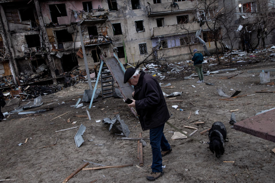 A man walks his dog in front of a residential block hit by an early morning missile strike Feb. 25 in Kyiv,. 