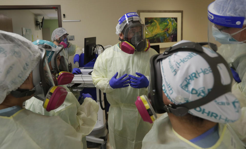 Medical personnel confer about COVID-19 patients at DHR Health, Wednesday, July 29, 2020, in McAllen, Texas. At DHR Health, the largest hospital on the border, roughly half of the 500 beds belong to coronavirus patients isolated in two units. A third unit is in the works. (AP Photo/Eric Gay)