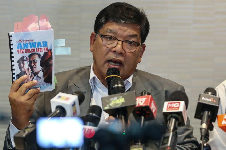 Johari holds up a copy of 'Mengapa Anwar Tak Boleh Jadi PM' during a press conference at PKR's headquarters in Petaling Jaya June 19, 2019. — Picture by Yusof Mat Isa