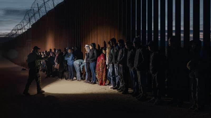 A group of migrants wait to be processed at the U.S.-Mexico border near San Diego, California