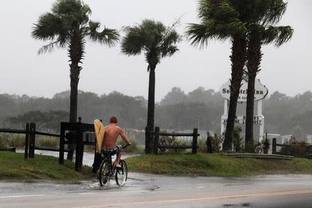 A surfer rides his bike down Atlantic Boulevard during the heavy rains of Tropical Storm Hermine as it passed through Garden City Beach, South Carolina, U.S. September 2, 2016. REUTERS/Randall Hill