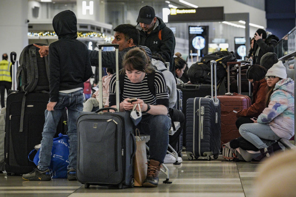 Pasajeros de Southwest Airlines se sientan con su equipaje en la zona de registro debido a retrasos y cancelaciones en el aeropuerto Laguardia, en Nueva York, el viernes 23 de diciembre de 2022. (AP Foto/Bebeto Matthews)