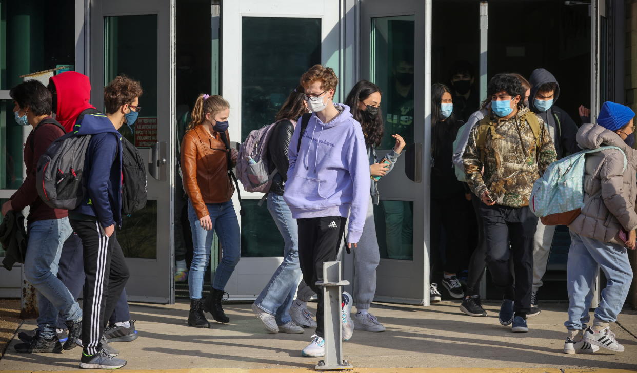 Students wearing masks walk out the doors of Washington-Liberty High School in Arlington, Virginia. 