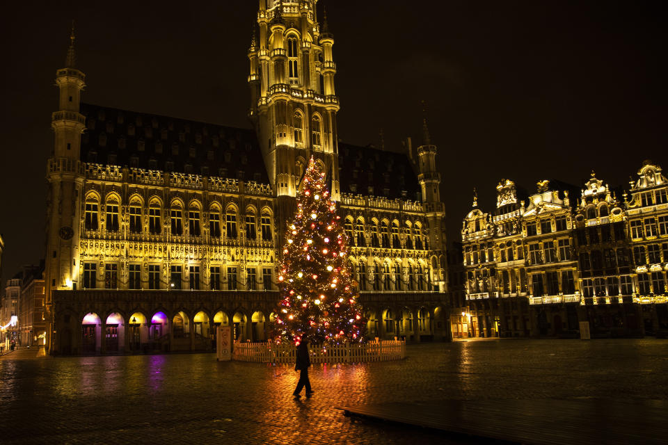 A man walks along a virtually empty Grand Place square during a curfew in downtown Brussels, Thursday, Dec. 31, 2020. As the world says goodbye to 2020, there will be countdowns and live performances, but no massed jubilant crowds in traditional gathering spots like the Champs Elysees in Paris and New York City's Times Square this New Year's Eve. The virus that ruined 2020 has led to cancelations of most fireworks displays and public events in favor of made-for-TV-only moments in party spots like London and Rio de Janeiro. (AP Photo/Francisco Seco)