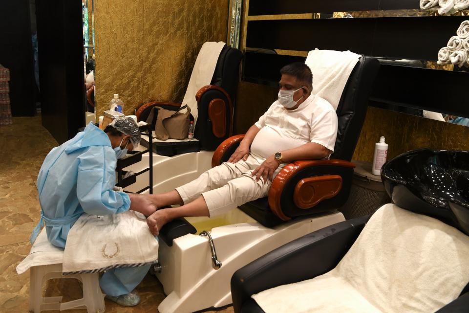 An employee of a hair salon wearing personal protective equipment (PPE) attends a customer, after the government eased a nationwide lockdown as a preventive measure against the COVID-19 coronavirus, in New Delhi on June 9, 2020. - India's national capital is staring at the possibility of at least half a million corona positive cases by the end of July, the deputy chief minister of Delhi told journalists on June 9. (Photo by Prakash SINGH / AFP) (Photo by PRAKASH SINGH/AFP via Getty Images)