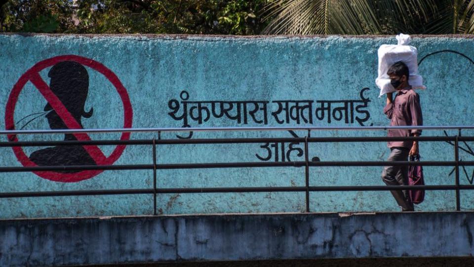 Un homme porte un masque pour se protéger du passage à pied du virus corona à côté du message sans cracher sur le mur de Marinelines, le 18 mars 2020 à Mumbai, en Inde.