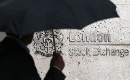 A man shelters under an umbrella as he walks past the London Stock Exchange in London, Britain August 24, 2015. REUTERS/Suzanne Plunkett
