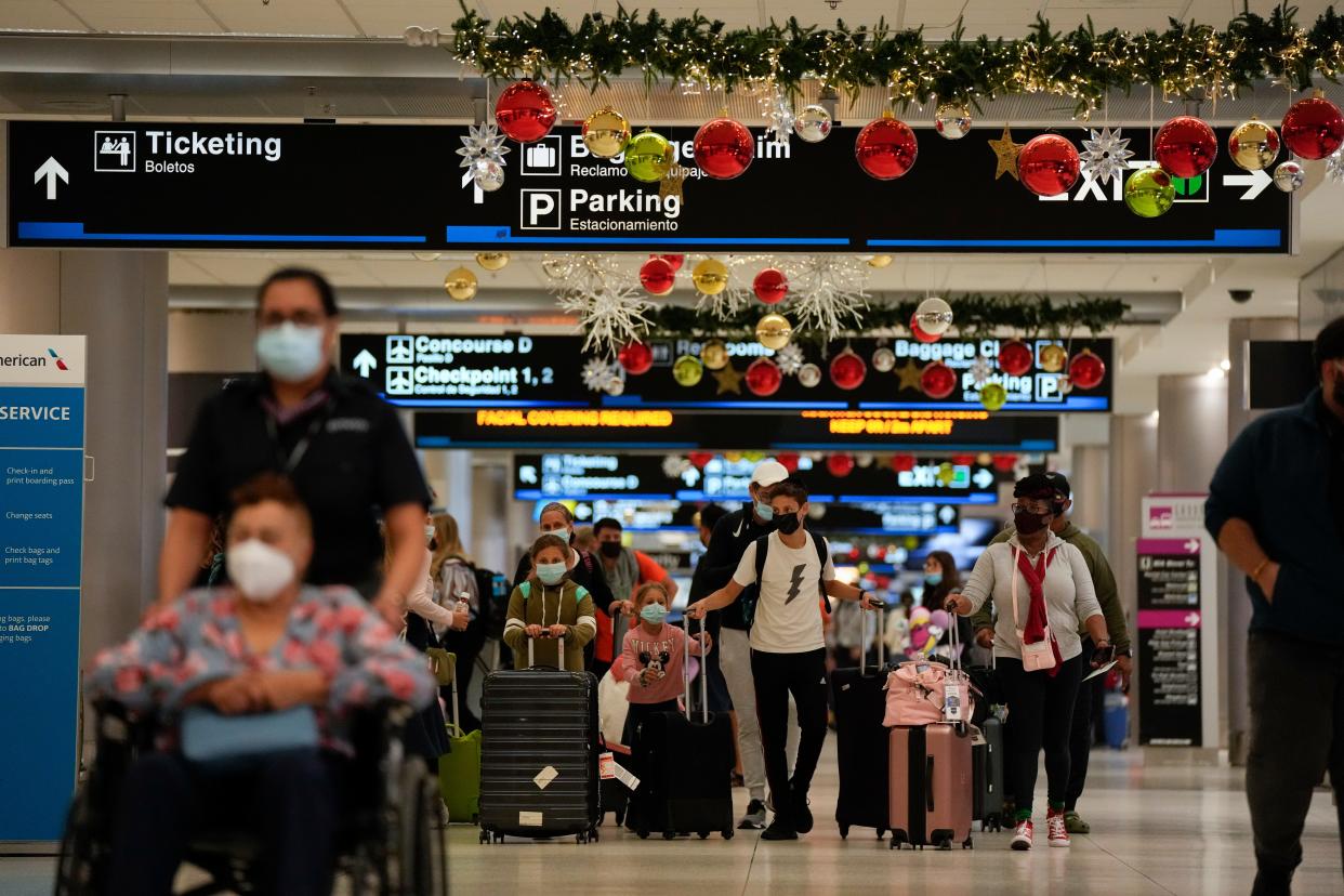 Travelers make their way through Miami International Airport, Monday, Dec. 27, 2021, in Miami. Thousands of flights worldwide were canceled or delayed on Monday, as airline staffing shortages due to the rapid spread of the omicron variant of COVID-19 continued to disrupt the busy holiday travel season. (AP Photo/Rebecca Blackwell)