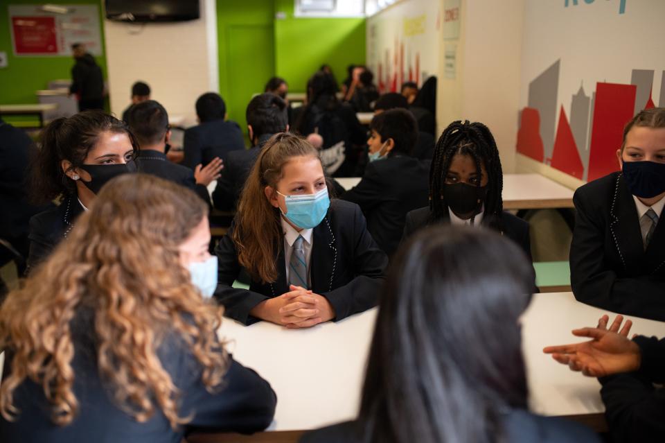 Year eight pupils wear face masks as a precaution against the transmission of the novel coronavirus as they chat before collecting their food in the dining room of Moor End Academy in Huddersfield, northern England on September 11, 2020. - Millions of children across England have returned to school after the Covid-19 lockdown with many schools introducing measures to enable as safe an environment as possible. (Photo by OLI SCARFF / AFP) (Photo by OLI SCARFF/AFP via Getty Images)