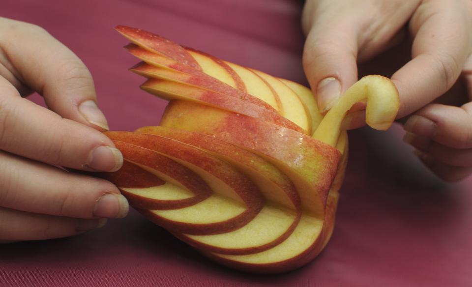 In this Sept. 28, 2011 photo, Rochel Goldstein holds an apple swan she just made. It was used in a decorative way as people prepared food for the Jewish New Year, Rosh Hashanah.