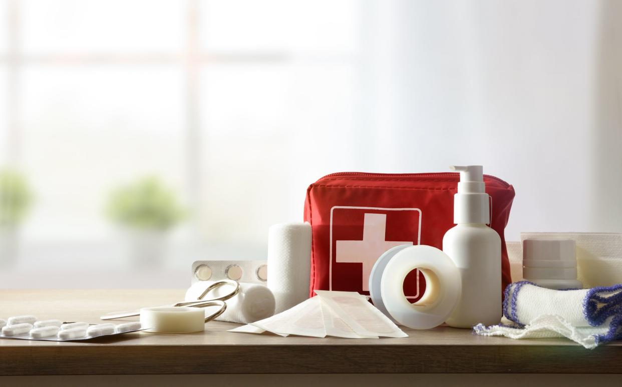 Basic home kit for cures in domestic accidents on a wooden table in a room. Horizontal composition. Front view.