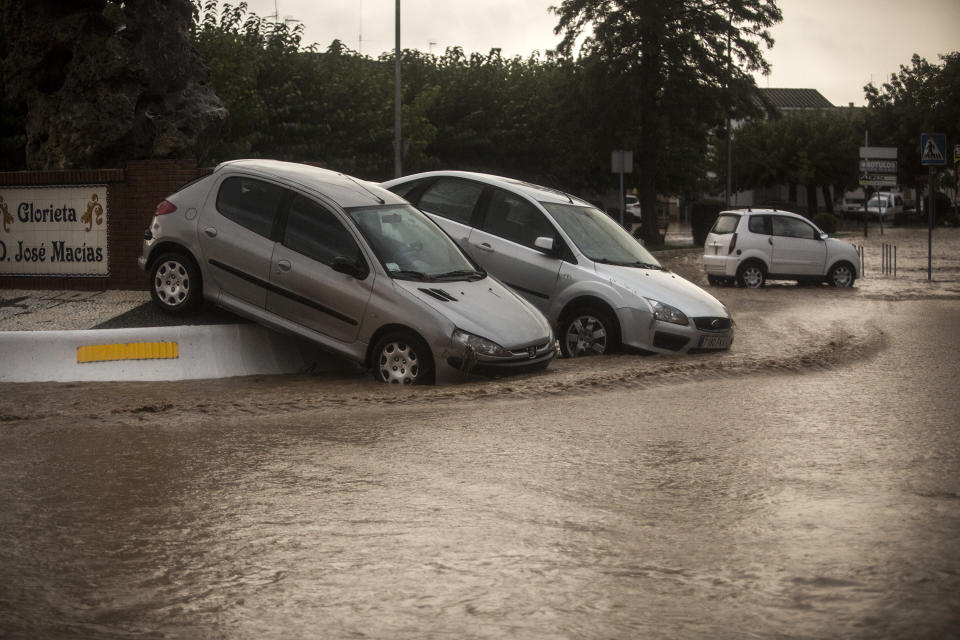 Cars rest on the curb after flood waters are receded in the village of Campillos, Spain, where heavy rain and floods have caused severe damage and the death of a firefighter according to Spanish authorities Sunday, Oct. 21 2018. Emergency services for the southern region of Andalusia say that the firefighter went missing when his truck overturned on a flooded road during heavy rains that fell through the night, and his body was found after a search Sunday morning. (AP Photo/Javier Fergo)