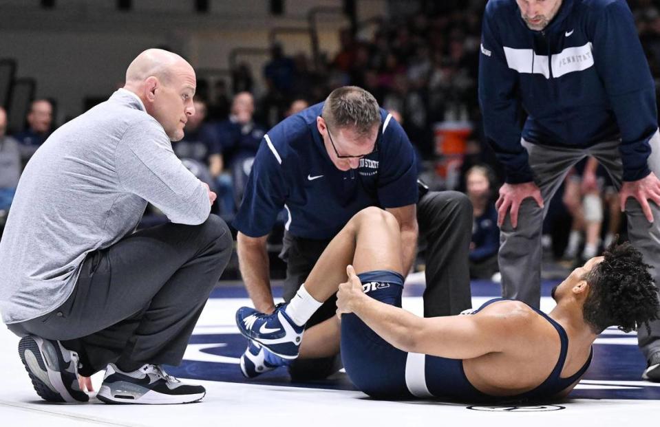 Penn State’s Carter Starocci (right) is treated by team trainer, Dan Monthly, as head coach Cael Sanderson (left) and head assistant coach Casey Cunningham look on. Starocci won the match by tech fall over Edinboro’s Joey Arnold at 174 pounds during Sunday’s final home wrestling meet at Rec Hall in University Park. Penn State defeated Edinboro, 55-0.