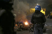 A police officer patrols as a bike burns during a protest called by Forza Nuova far right group against the government restriction measures to curb the spread of COVID-19, in Rome Saturday, Oct. 24, 2020. A midnight-to-5 a.m. curfew in Italy's Lazio region, which includes Rome, begins on Friday and lasts for 30 days, under orders from regional governor Nicola Zingaretti. (Cecilia Fabiano/LaPresse via AP)