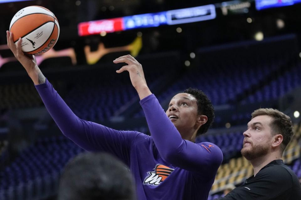 Phoenix Mercury center Brittney Griner shoots a ball under pressure from a staff member as she warms up.