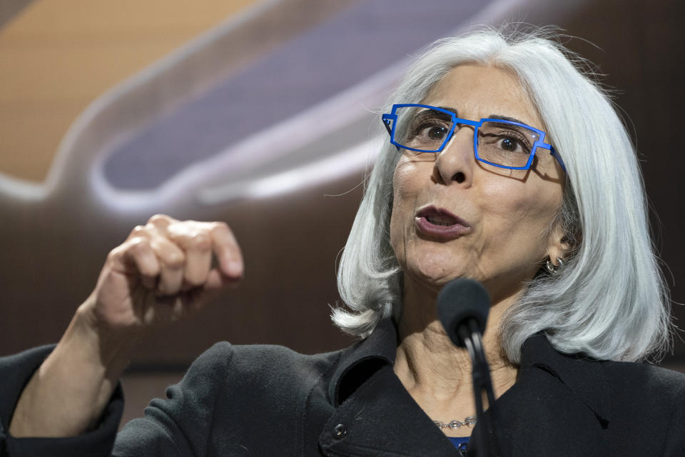 Arati Prabhakar, in royal blue-framed glasses, at the microphone.