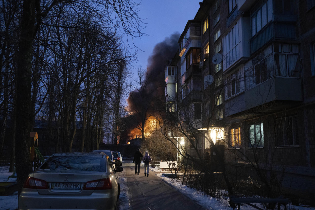 Residents watch at a burning infrastructure project hit during a Russian drone night strike in Kyiv, Ukraine, Monday, Dec. 19, 2022. (AP Photo/Efrem Lukatsky)