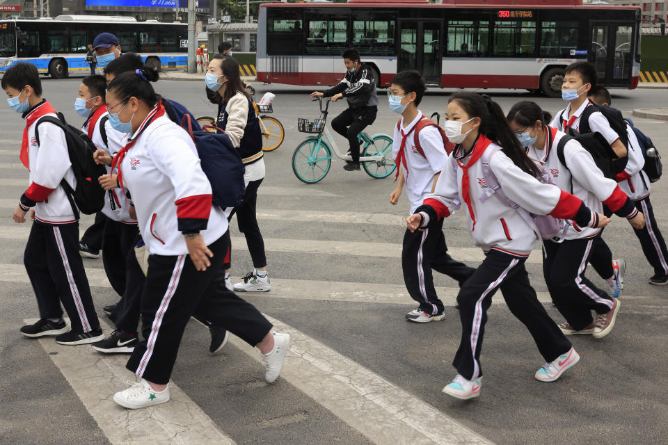 School children wearing masks cross a busy traffic intersection in Beijing on Thursday, April 29, 2021. China's population grew last year, the government said Thursday, following a news report a once-a-decade census might have found a decline, possibly adding to downward pressure on economic growth. (AP Photo/Ng Han Guan)