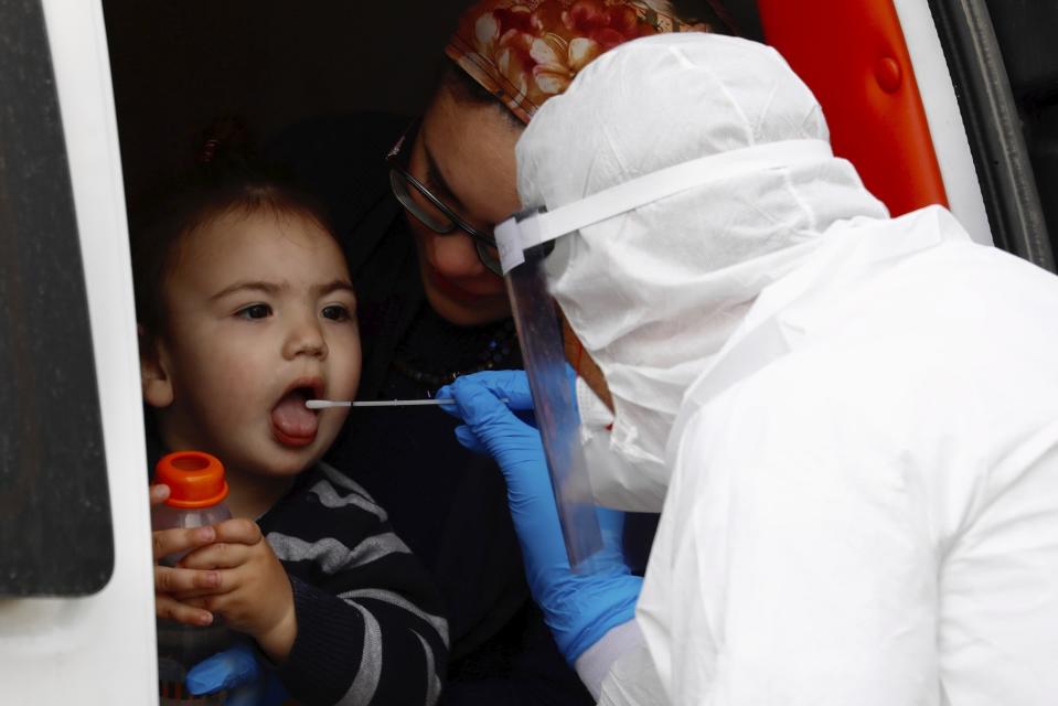 An ultra-Orthodox Jewish boy receives a COVID-19 test by a medical personnel wearing protective gear as part of the government's measures to stop the spread of the coronavirus in the orthodox city of Bnei Brak, a Tel Aviv suburb, Israel, Tuesday, March 31, 2020. (AP Photo/Ariel Schalit)