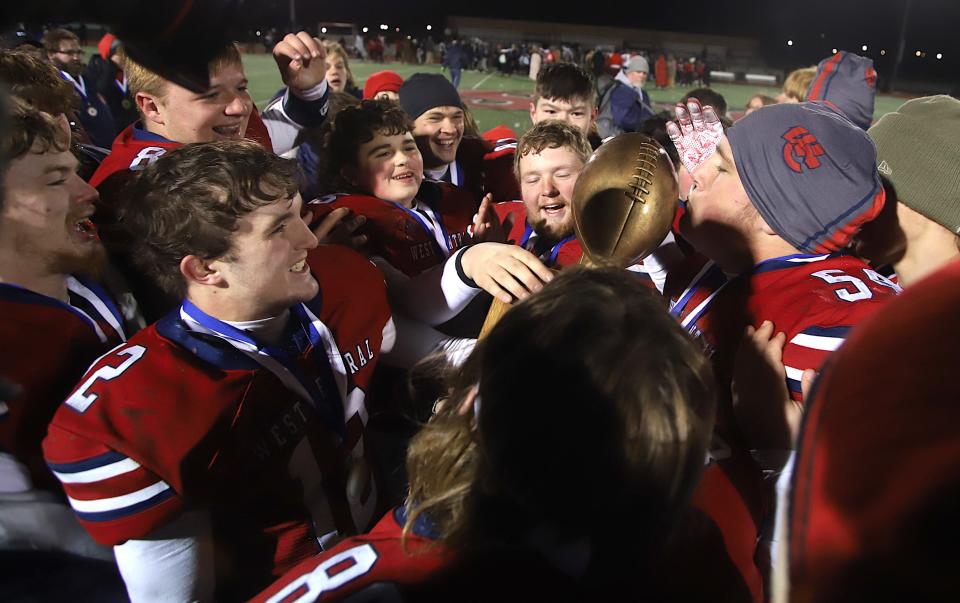 West Central’s Blake Cole (54), right, kisses the Illinois 8-player championship trophy as he celebrates with teammates after the victory against Amboy Friday in Monmouth, Illinois.