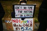 This photo taken on February 29, 2020 shows a protester holding placards during a demonstration against the Olympics, Prime Minister Shinzo Abe and nuclear energy, near the "J-Village" which will host the start of the Olympic torch relay in Naraha, Fukushima prefecture. - Tokyo 2020 CEO Toshiro Muto said on February 26 the torch relay scheduled to begin March 26 in Fukushima and travel across the country would not be cancelled, though he acknowledged adjustments might be necessary, due to the COVID-19 outbreak. (Photo by CHARLY TRIBALLEAU / AFP) (Photo by CHARLY TRIBALLEAU/AFP via Getty Images)