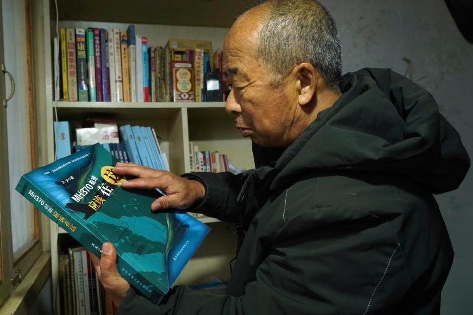 Chinese farmer Li Eryou looks at a book written about the missing Malaysia Airlines MH370 flight from a bookshelf of his son's former room at a village in Handan in northern China's Hebei province (Copyright 2024 The Associated Press. All rights reserved)