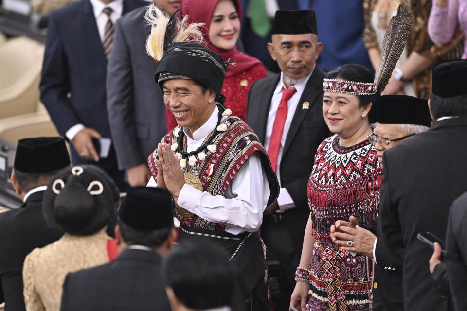 Indonesian President Joko Widodo, left, in traditional attire from Tanimbar Islands of Maluku province, walks with House Speaker Plan Maharani in traditional outfit from West Kalimantan, upon arrival to deliver his State of the Nation Address ahead of the country's Independence Day, at the parliament building in Jakarta, Indonesia, Wednesday, Aug. 16, 2023. (Adek Berry/Pool Photo via AP)