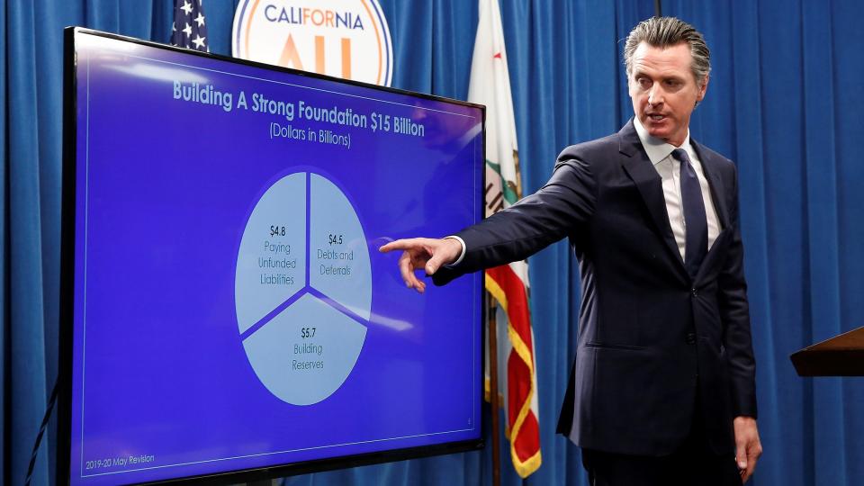 In this May 9 photo, Gov. Gavin Newsom gestures to a chart as he discusses his revised state budget during a news conference in Sacramento. California lawmakers and Gov. Newsom broadly agree on a $213 billion state budget that spends more on immigrants and the poor. But they're still debating over how far those program expansions should go and how to pay for them. They're now in the final days of negotiations ahead of a June 15 deadline.