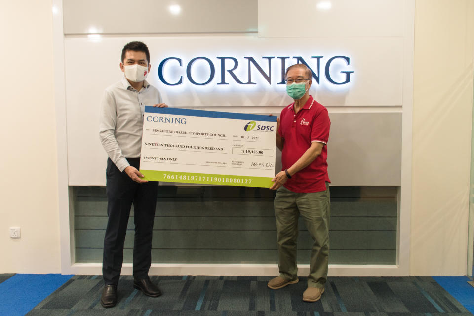 Corning International (ASEAN region) general manager Ho Cheong Tong (left) hands a cheque of $19,426 to Singapore Disability Sports Council honorary secretary Ho Cheng Kwee. (PHOTO: SDSC)