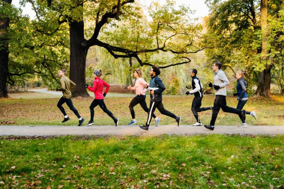 A group of joggers racing against each other on pedestrian walk way at the park via Getty Images/<br>Tom Werner