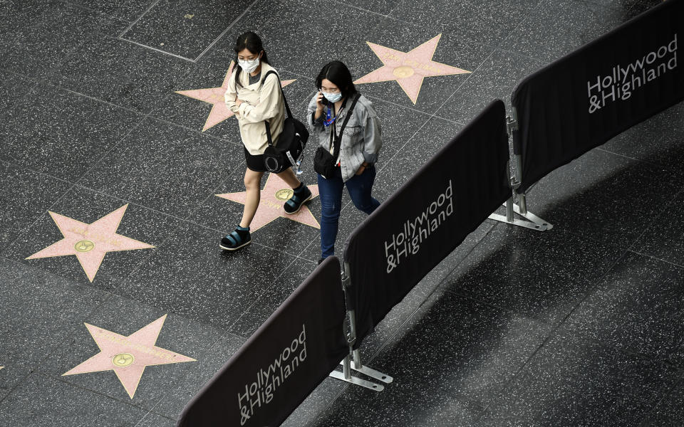 Pedestrians wear masks as they walk down Hollywood Boulevard, Thursday, March 12, 2020, in the Hollywood section of Los Angeles. For most people, the new coronavirus causes only mild or moderate symptoms. For some it can cause more severe illness. (AP Photo/Chris Pizzello)