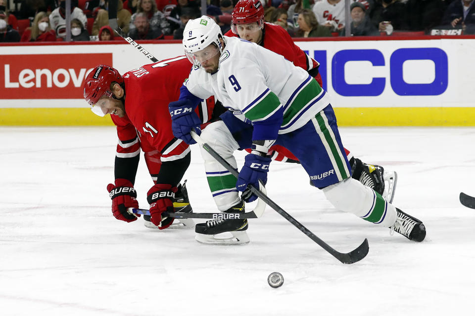 Vancouver Canucks' J.T. Miller (9) wins a battle for the puck against Carolina Hurricanes' Jordan Staal (11) during the second period of an NHL hockey game in Raleigh, N.C., Saturday, Jan. 15, 2022. (AP Photo/Karl B DeBlaker)