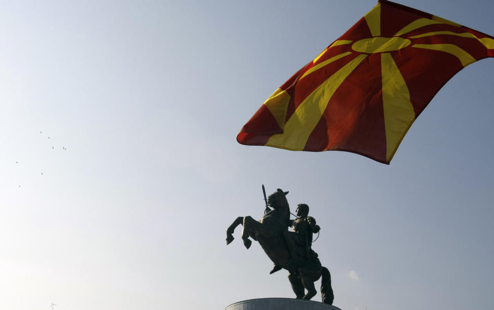 In this Oct. 23, 2012 photo Macedonian flag flies in front of the monument of the "Warrior on a Horse", in downtown Skopje, Macedonia, which is believed to depict Alexander the Great. Grandiose buildings, monuments, fountains and bridges are dotting the city center as part of a government project called Skopje 2014, officially intended to rebuild a city that lost many of its landmarks in a 1963 earthquake. (AP Photo/Darko Vojinovic)