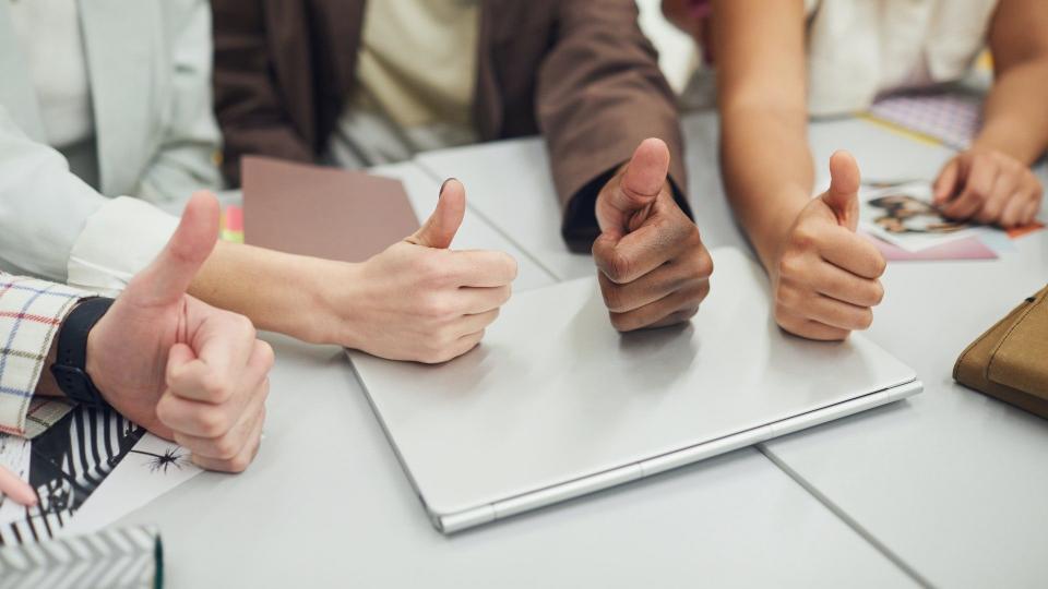 Vier positiv gestimmte Menschen aus einer Arbeitsgruppe zeigen den Daumen nach oben