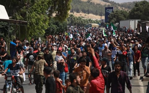 Syrians from the country's northern countryside demonstrate by the Bab al-Hawa crossing between Turkey and Syria's northwestern Idlib province  - Credit: AFP