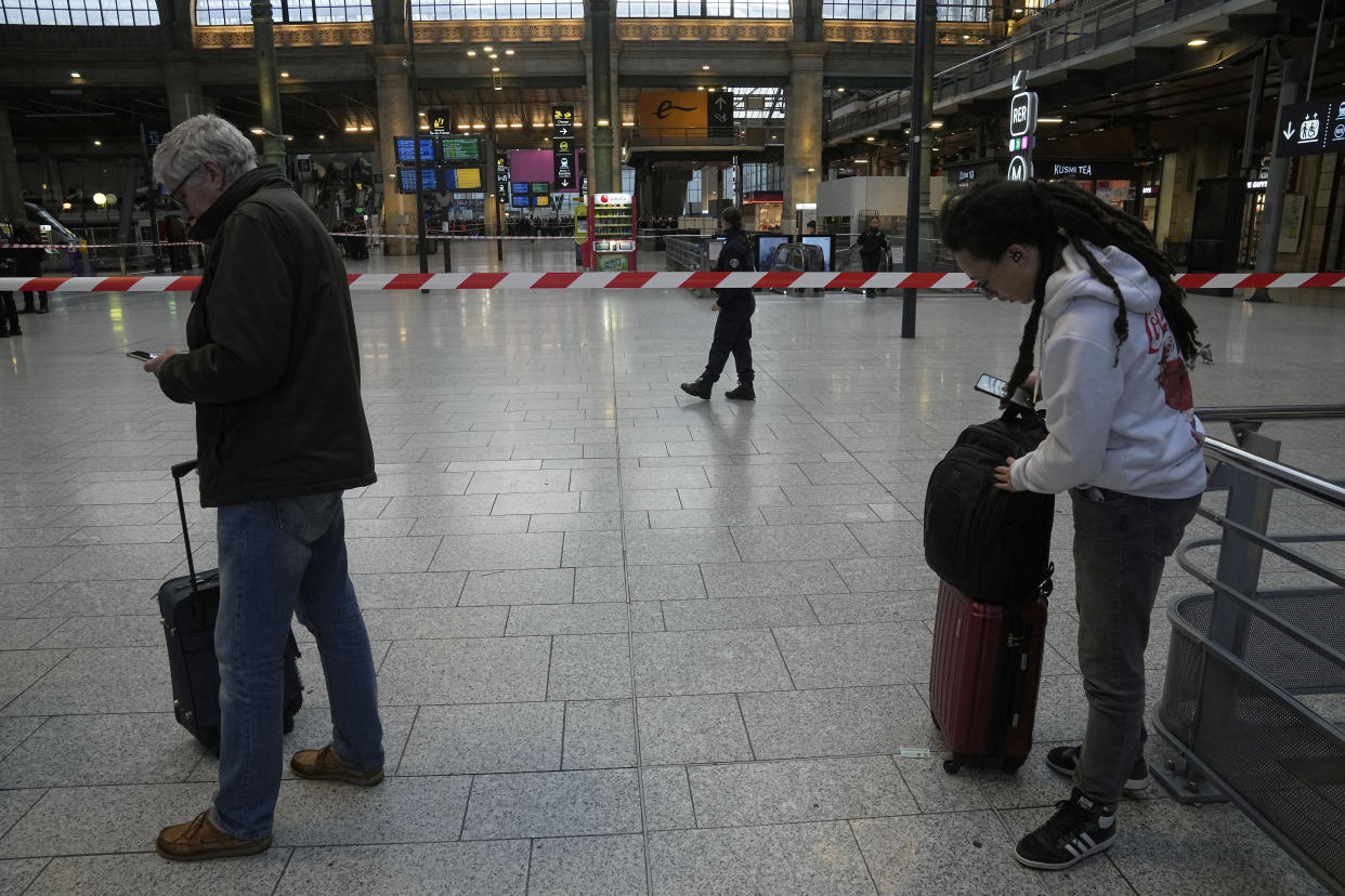 Travelers what behind the police tape at the Gare du Nord train station, Wednesday, Jan. 11, 2023 in Paris. (AP Photo/Michel Euler)