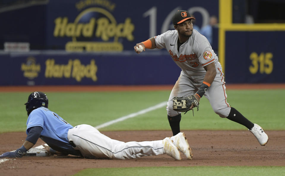 Tampa Bay Rays' Manuel Margot, left, slides into third base on a single hit by Yandy Diaz as Baltimore Orioles' Maikel Franco looks to throw to first base during the third inning of a baseball game Sunday, June 13, 2021, in St. Petersburg, Fla. (AP Photo/Steve Nesius)