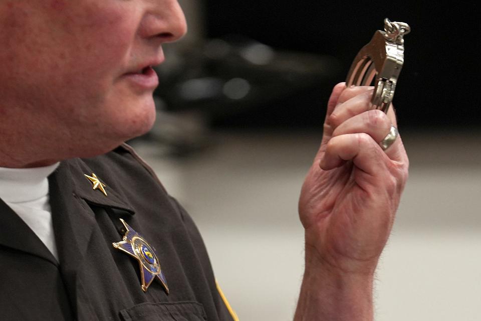 Marion County Sheriff Kerry Forestal holds up his handcuffs while speaking at a news conference Wednesday, Aug. 30, 2023, at the Community Justice Campus in Indianapolis. The news conference was held to release video surveillance footage of events before and after Deputy John Durm's July 10 murder, and announce changes being implemented as a result of the incident.