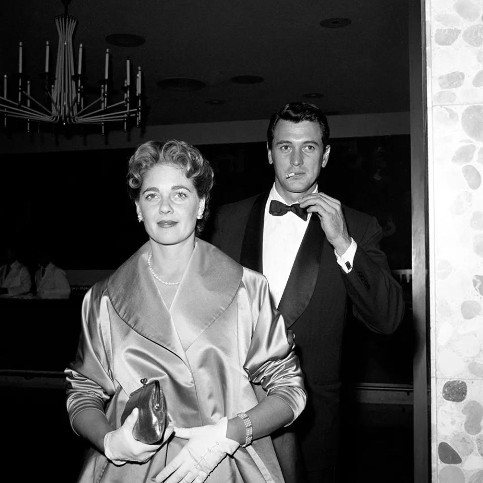 Rock Hudson walking behind his wife Phyllis Gates while smoking a cigarette