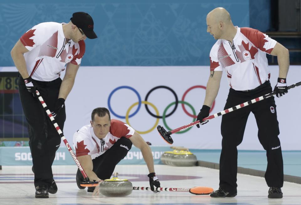 Canada's second E.J. Harnden delivers a stone as lead Ryan Harnden (L) and vice Ryan Fry (R) prepare to sweep during their men's curling round robin game against the U.S. in the Ice Cube Curling Centre at the Sochi 2014 Winter Olympic Games February 16, 2014. REUTERS/Ints Kalnins (RUSSIA - Tags: SPORT OLYMPICS SPORT CURLING)