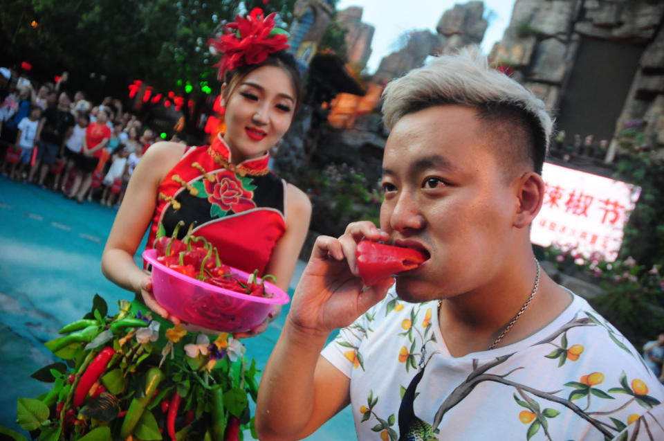 A man competes eating peppers at Song Dynasty Town on July 20, 2016 in Hangzhou, Zhejiang Province of China. As the ground temperature reached 40 degrees Celsius in Hangzhou, tourists competed eating peppers while sitting in the ice buckets to feel hot and cool at the same time in the Song Dynasty Town scenic area.&nbsp;